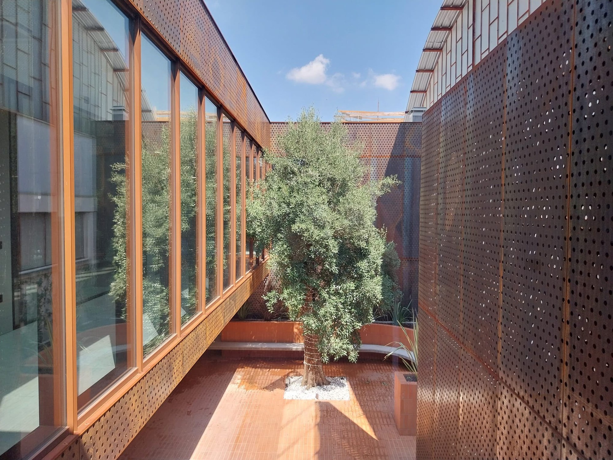 La corte interna: facciata vetrata e superfici in Corten